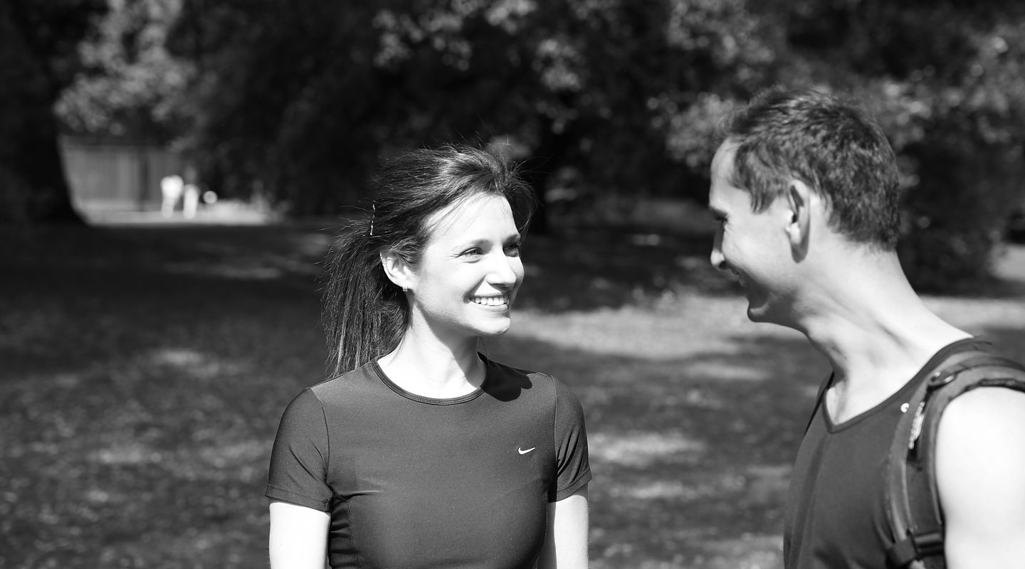 Roland and a client smiling at each other in the park, in black and white.