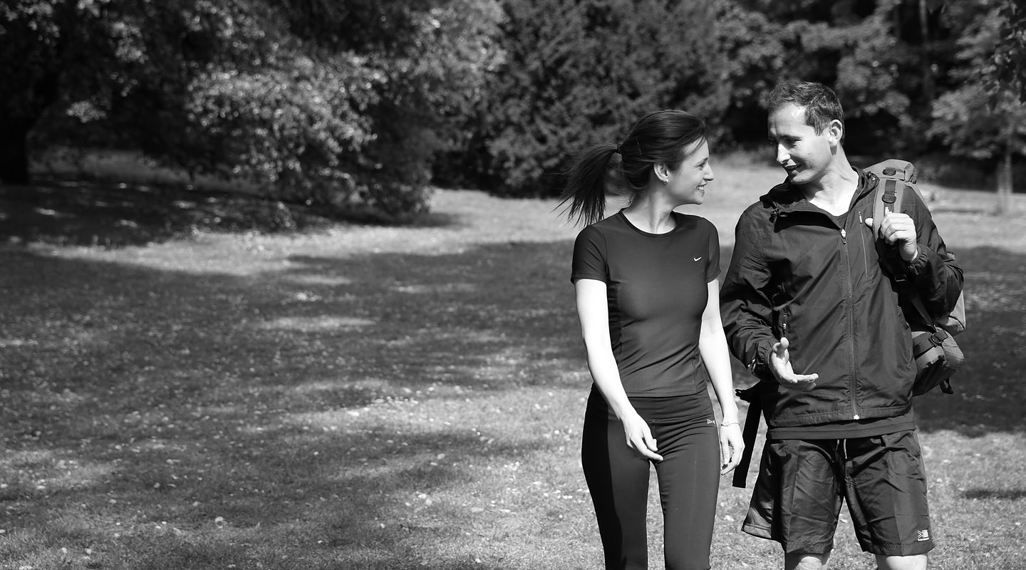 Roland walking and talking with a client in the park, in black and white.